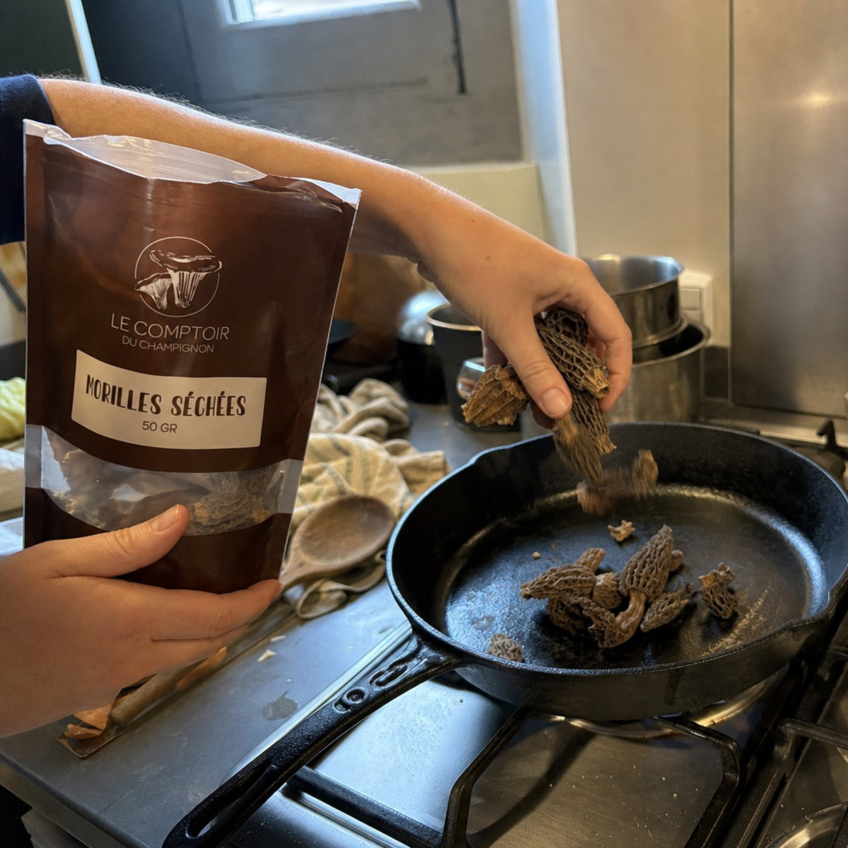 Morilles séchées versées dans une poêle en fonte avec le sachet Le Comptoir du Champignon